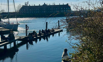 Steg mit Segelbbot und jungen Menschen am Wasser