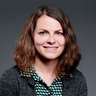 Eine Frau mit langen, braunen Haaren. Sie lächelt in die Kamera.