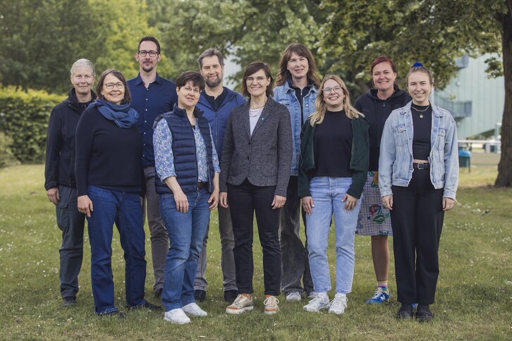Das Team des Servicebereichs QHD steht für ein Gruppenfoto auf einer Wiese.