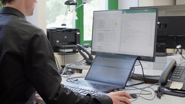 The image shows a staff member working at a computer.