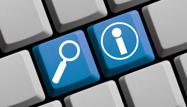 Computertastatur mit hervorgehobenen blauen Tasten, auf denen eine Lupe und ein Informationssymbol zu sehen sind.