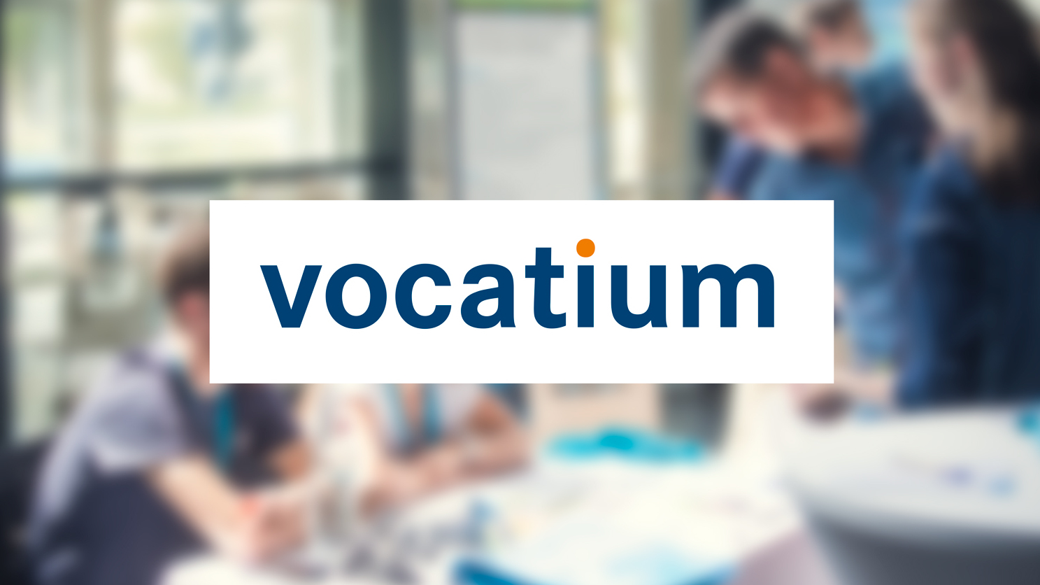 Logo „vocatium“ auf weißem Hintergrund vor einem unscharfen Foto mehrerer Personen bei einem Gespräch.