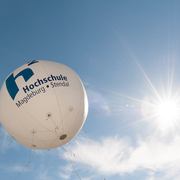 großer Ballon mit Hochschullogo am blauen Himmel