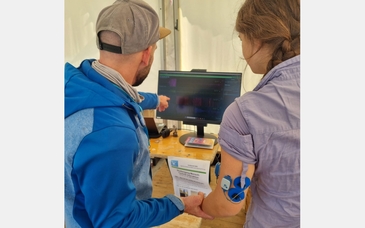 Mitarbeiter zeigt interessierter Person das EMG, welches an ihr angeschlossen ist.