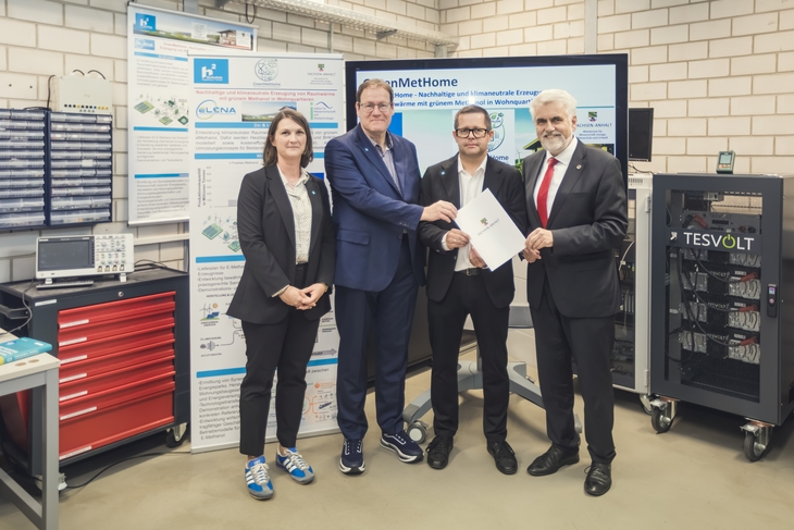Prof. Dr.-Ing. Jürgen Wiese (left) and Prof. Dr.-Ing. Przemyslaw Komarnicki (right) with Minister of Science Prof. Dr. Armin Willingmann (SPD) in a laboratory hall. Photo: Magdeburg-Stendal University of Applied Sciences/Matthias Piekacz  The three men are holding the funding notification and smiling.