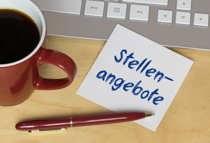 Notizzettel mit der Aufschrift „Stellenangebote“ neben Tastatur, Kaffeetasse und Stift