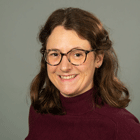 Ein Foto von Marina Schütz - einer freundlich lächelnden Frau mit braunen schulterlangen Haaren und Brille